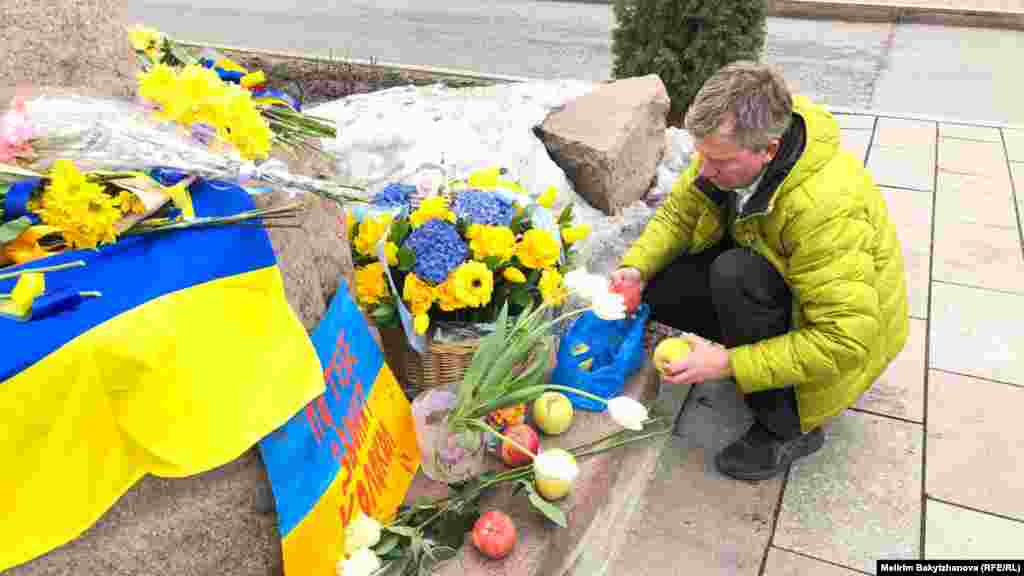 Украин ақыны Тарас Шевченконың ескерткіші алдына алма қойып жатқан адам. Ресей Украинаға басқыншылық соғыс ашқанына бір жыл толған күні осы ескерткішке адамдар гүл, алма, Украина туы мен &quot;Соғыс тоқтасын!&quot; деген жазуы бар плакаттар қойды.